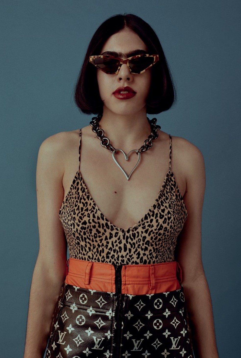 Lola veste body, R$ 80, Forever 21; saia laranja, R$ 457, Diego Favaro; saia preta com logo, R$ 14 mil, Louis Vuitton. Óculos, R$ 1.290, Prada. (Foto: João Arraes) — Foto: Glamour