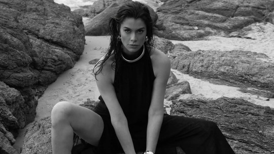 Alinne Moraes posa com vestido preto de fenda ousado em ensaio à beira-mar