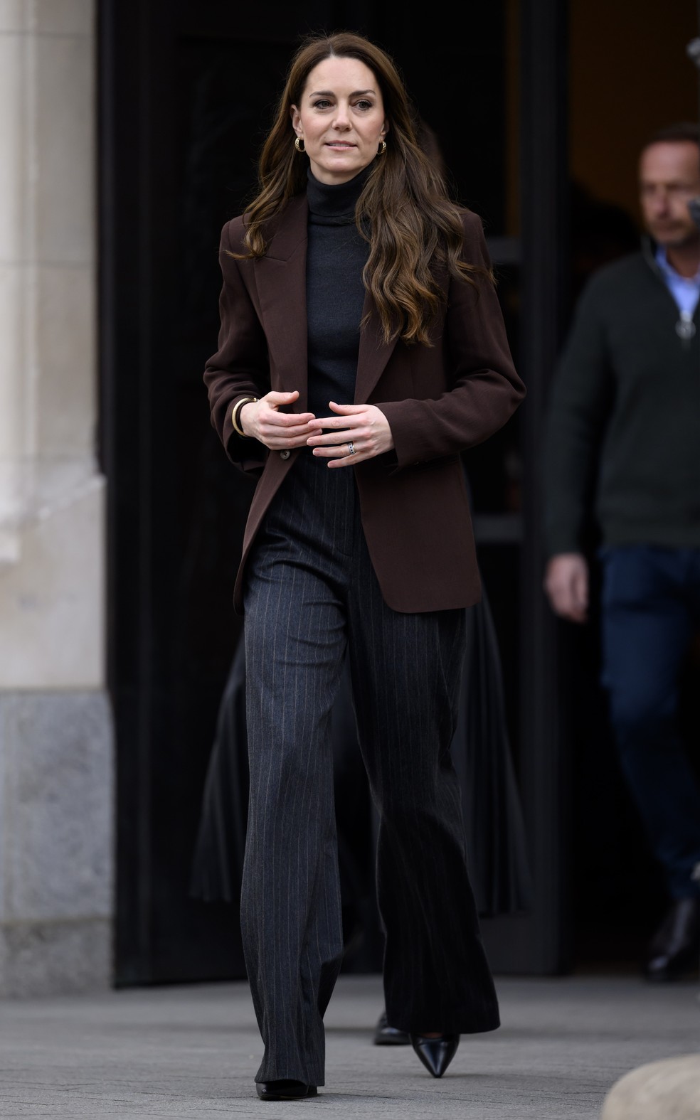 Kate Middleton aposta no blazer alongado marrom com calça azul marinho — Foto: Getty Images
