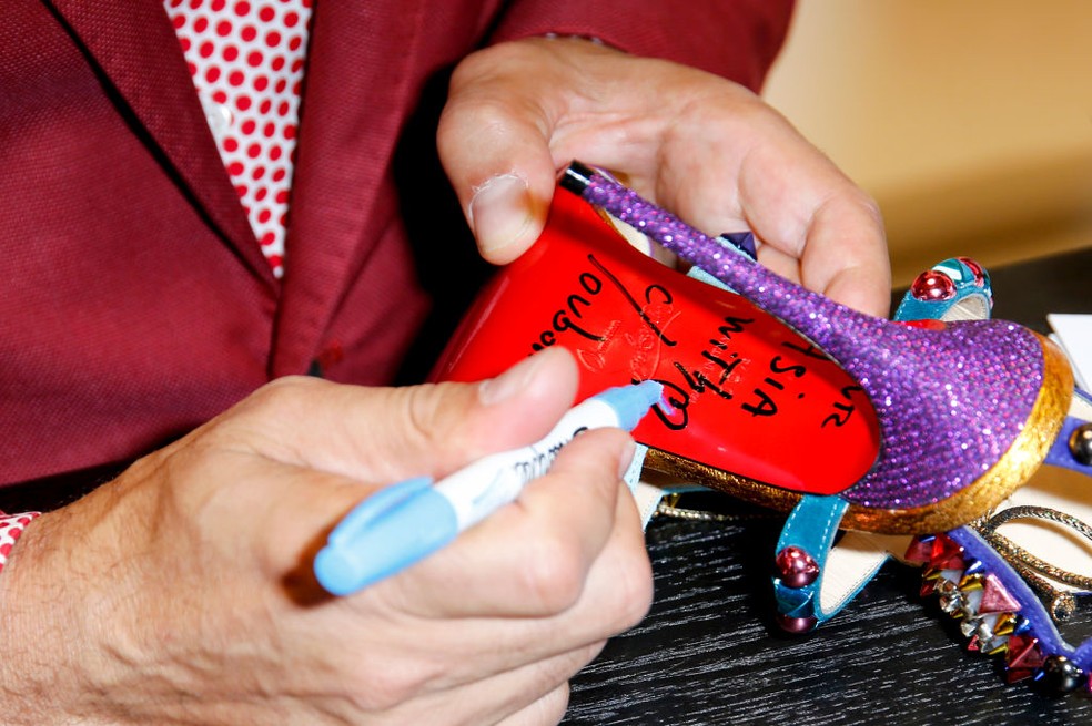 Christian Louboutin autografa a famosa sola vermelha em 2017 — Foto: Getty Images